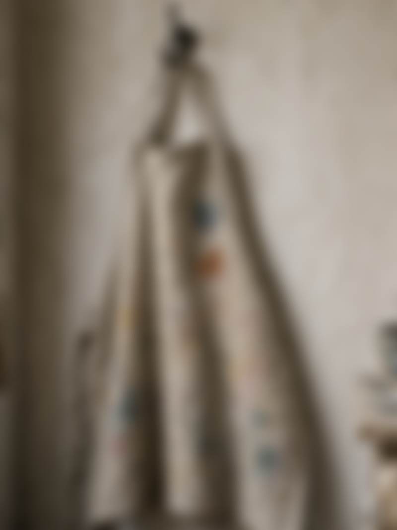 A paint-stained apron on a studio hook.
