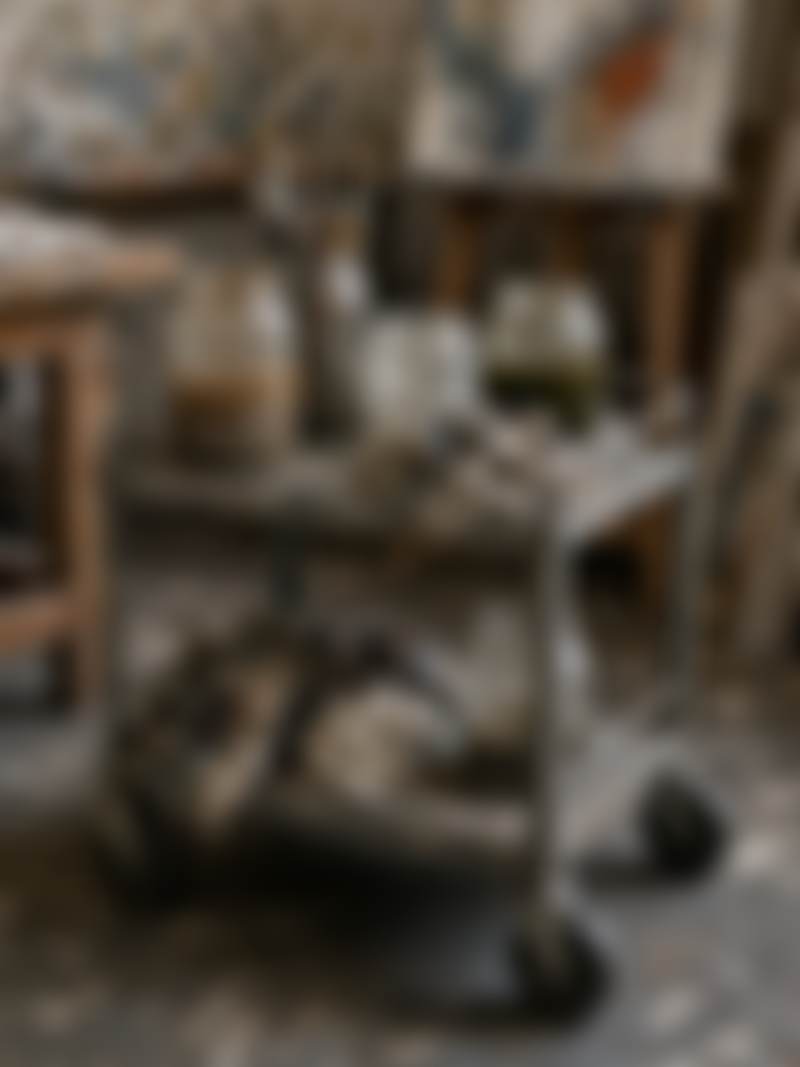A small rolling cart of jars and rags.