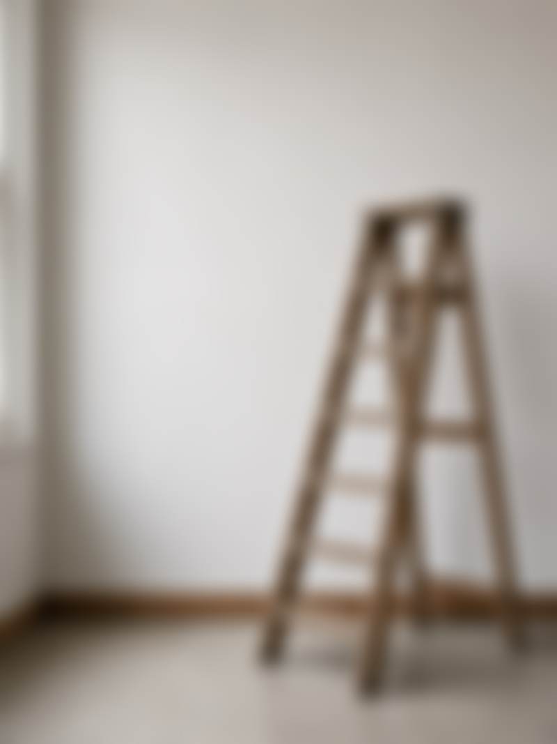 A wooden ladder leaning on a studio wall.