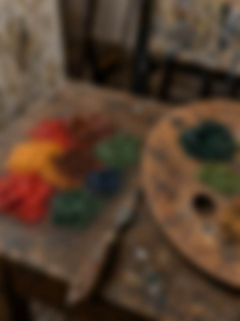 A wooden palette with mixed paint on a studio table.