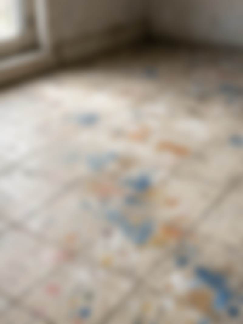 A worn tile floor with paint drops.