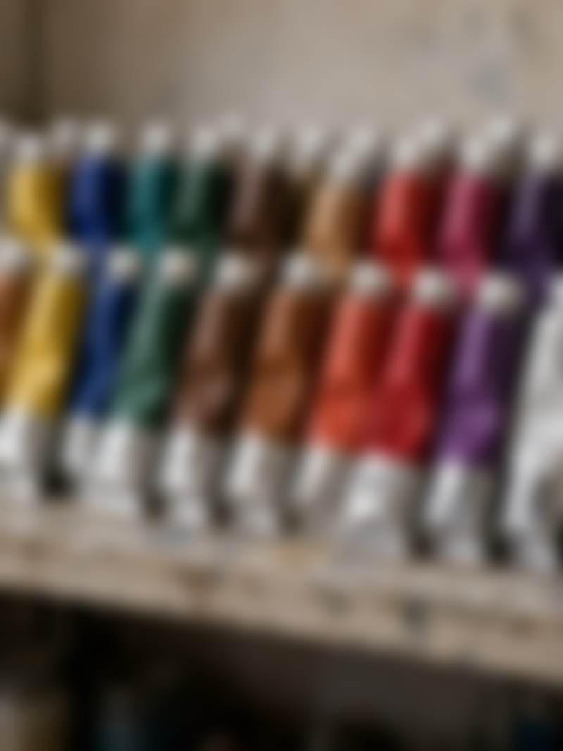 A shelf of paint tubes, labels turned away.